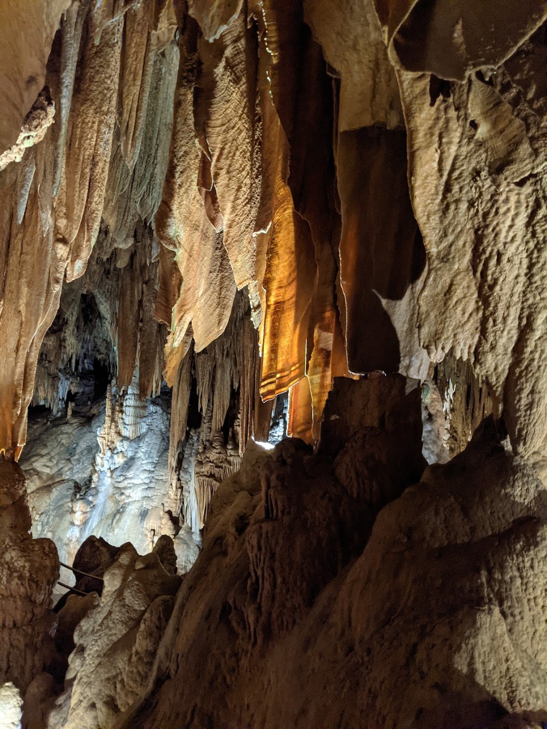 Rock formations hanging from the ceiling, some are partially transparent and look like hanging fabric.