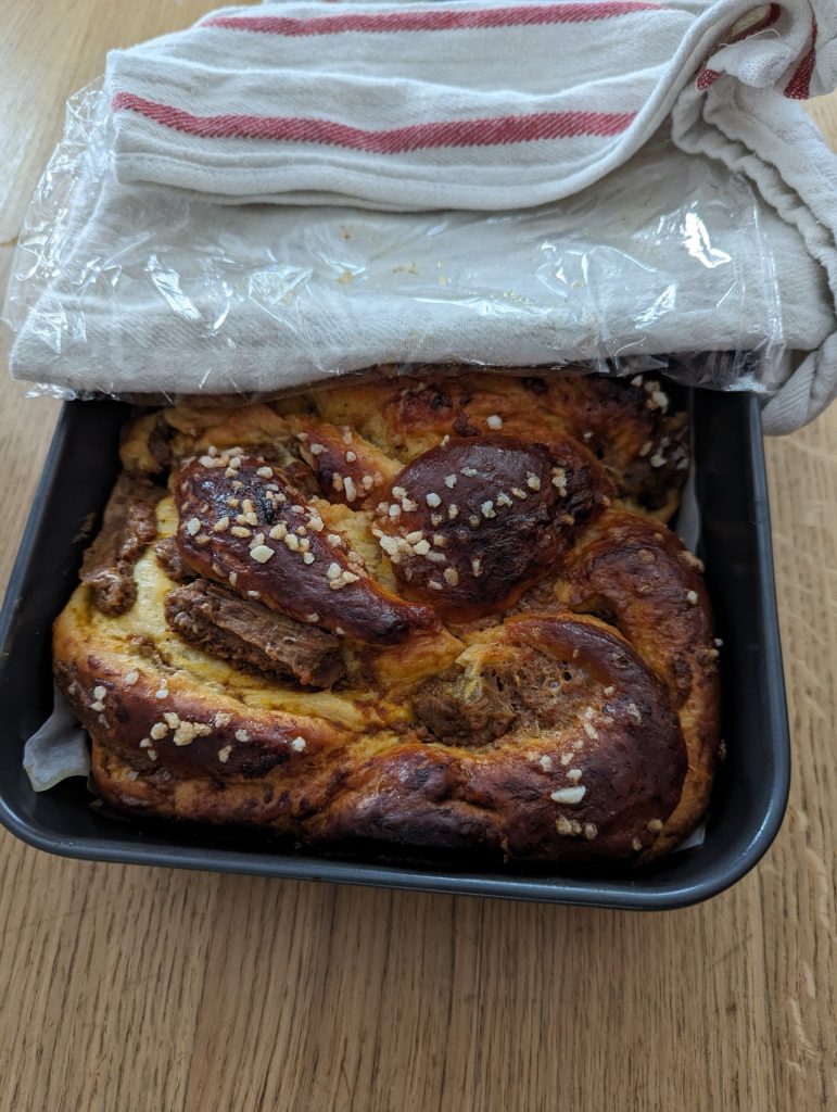 A braided loaf in a pan with pearl sugar topping.