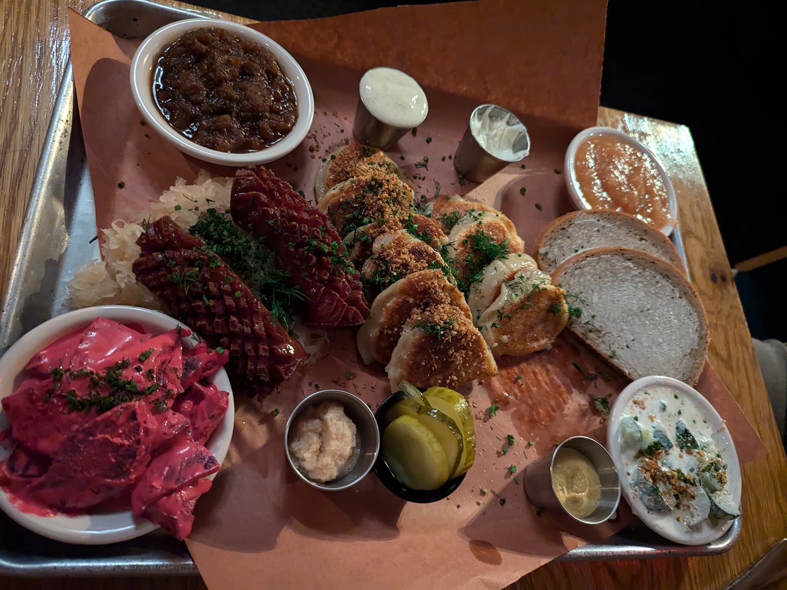 A large tray of food featuring Polish food - kielbasa, pierogi, sauerkraut, and other sides.