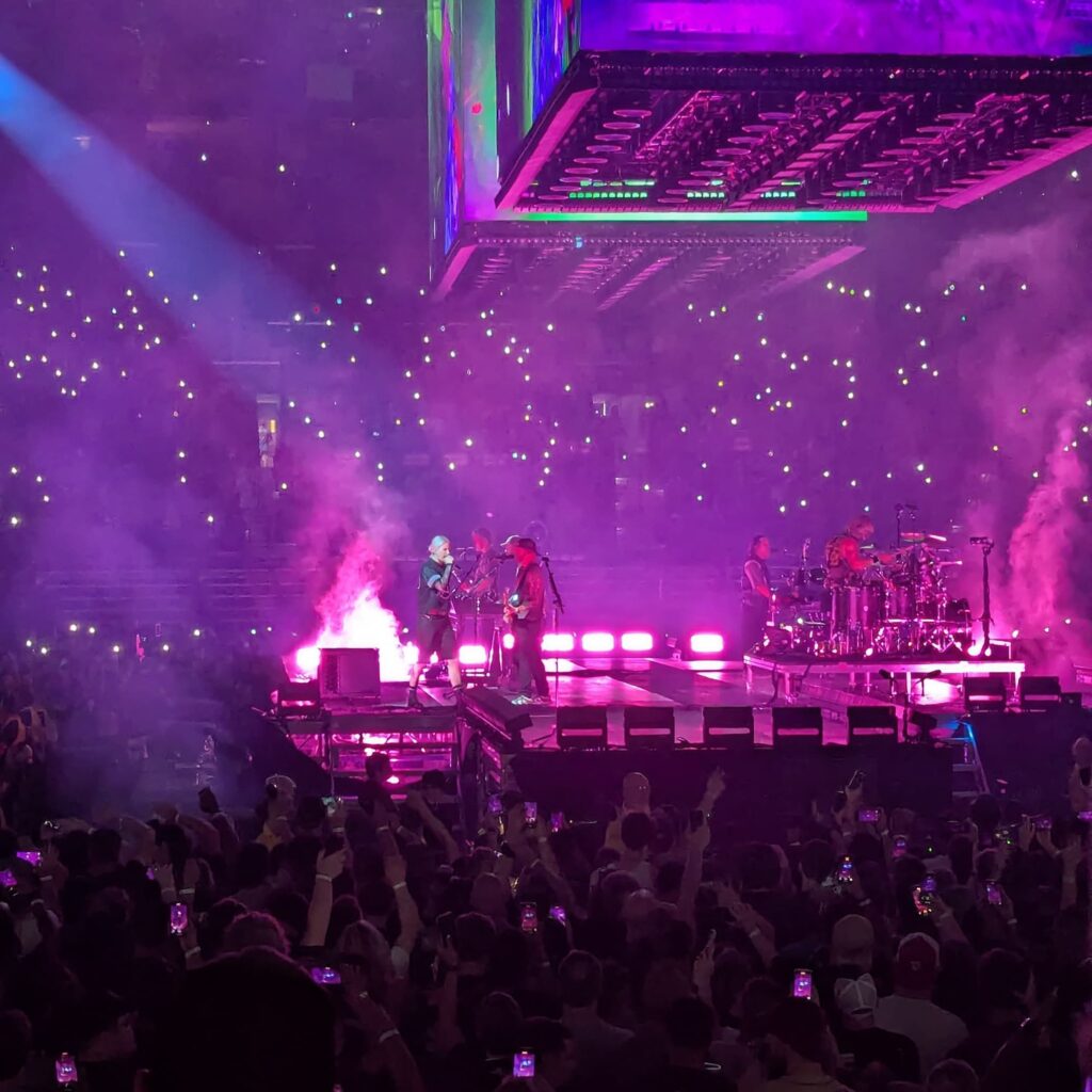 Linkin Park on stage from our seats with all the lights pink, the singer is spotlit walking around.