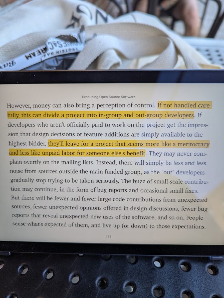 My iPad screen open to Producing Open Source Software, with a section highlighted that says "If not handled carefully, this can divide a project into in-group and out-group developers […] they'll leave for a project that seems more like a meritocracy and less like unpaid labor for someone else's benefit."