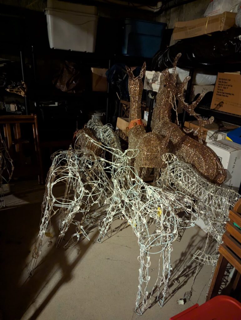 A poorly lit basement, the light is coming from behind the camera highlighting 8+ Christmas reindeer decorations.