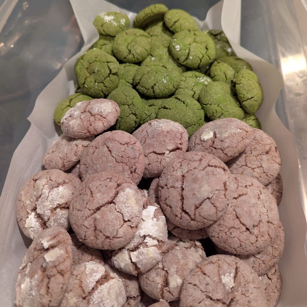 A container of cookies, two kinds: one is a pale pink color, the other a bright green.